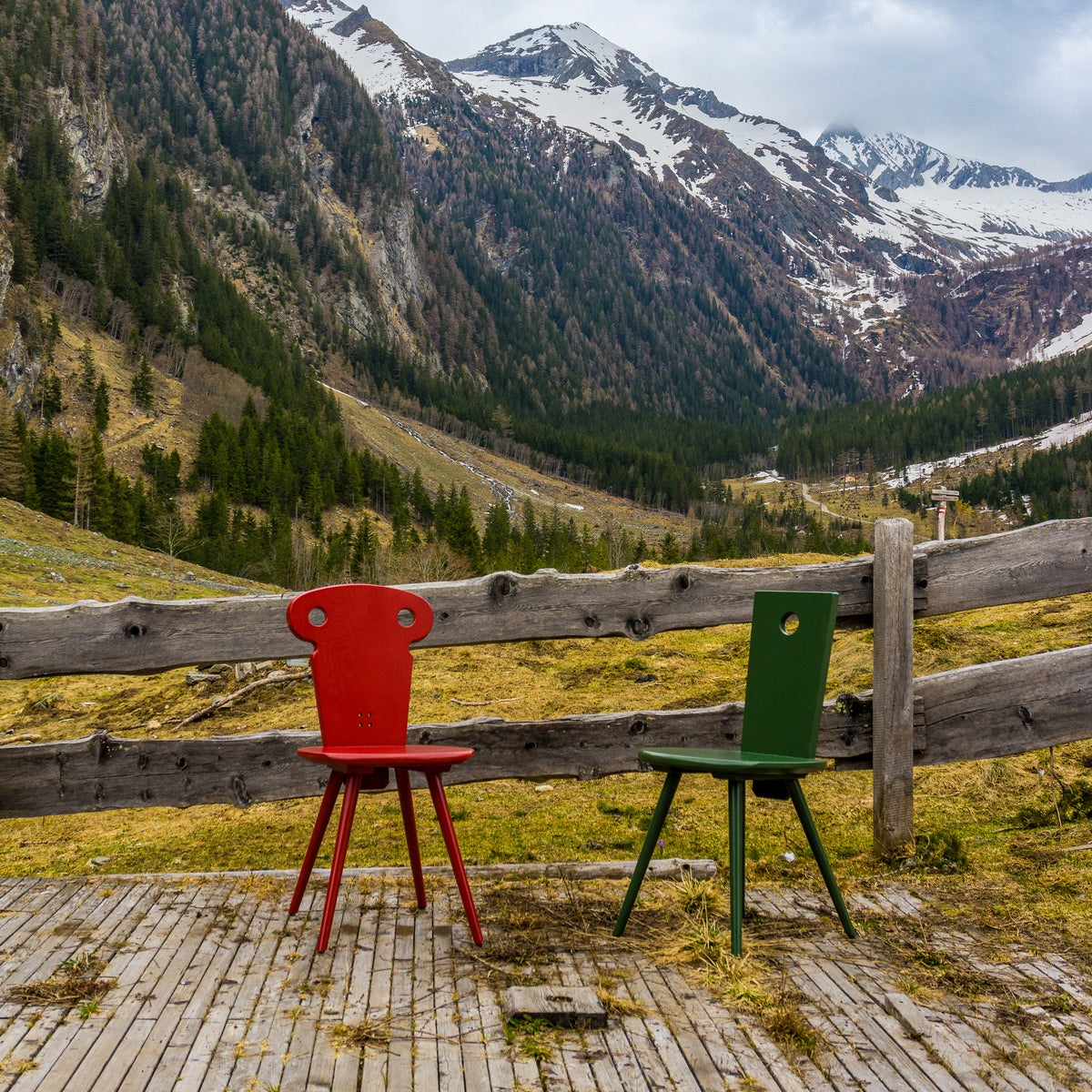 Watzmann Resi in Glutrot und Watzmann Magnus in Jagagrün vor alpinen Hintergrund.