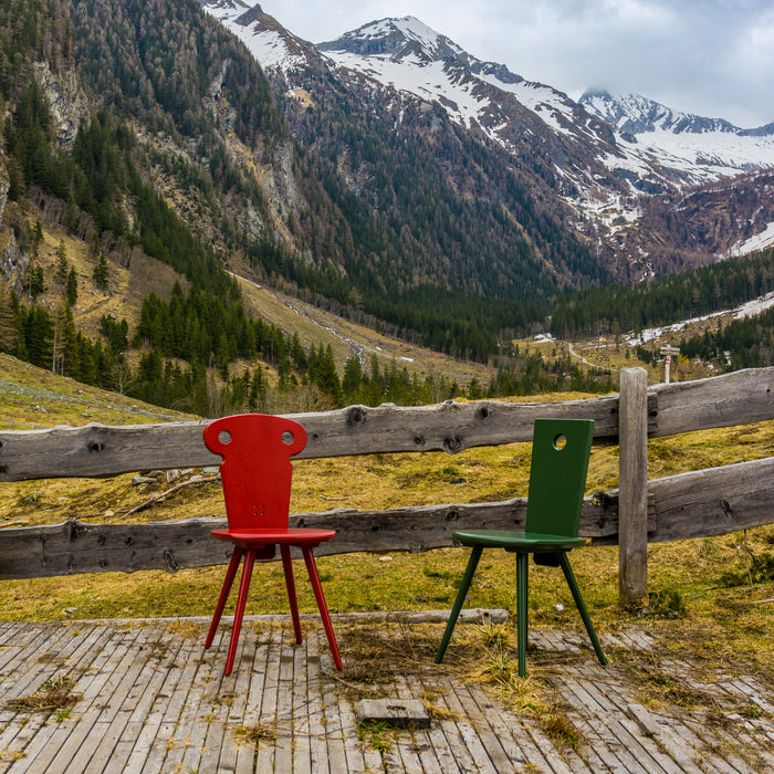 Watzmann Resi in Glutrot und Watzmann Magnus in Jagagrün vor alpinen Hintergrund.